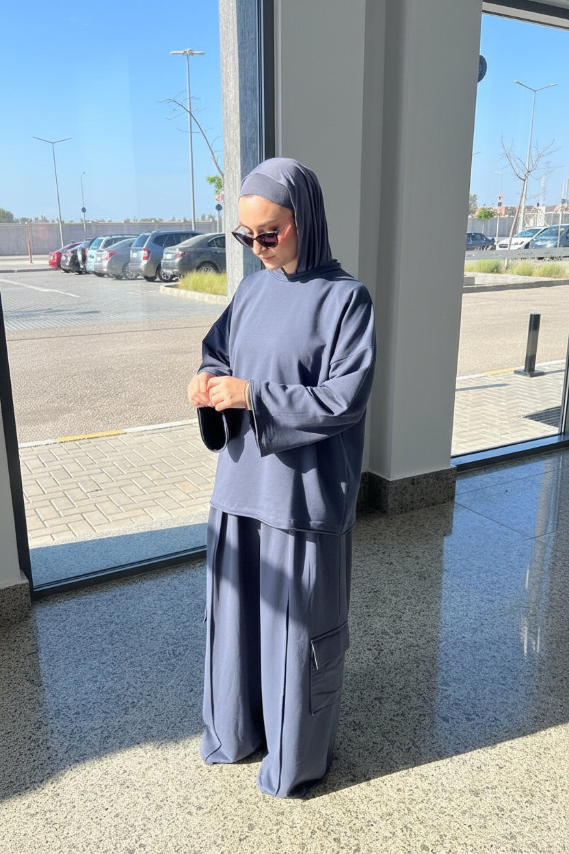 Person wearing a gray outfit standing outside near a building.